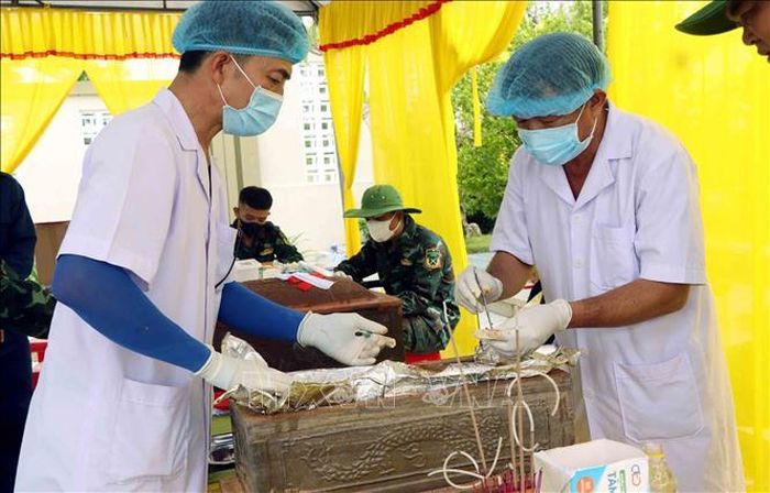 Lực lượng chức năng tiến hành lấy mẫu sinh phẩm hài cốt liệt sĩ. Ảnh: Công Tường/TTXVN