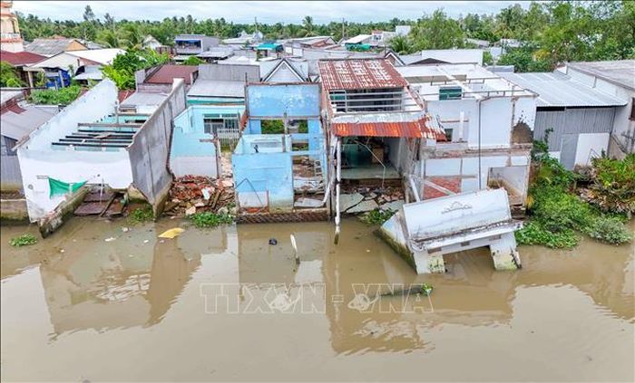 Con đường bê tông ven rạch Mang Cá bị sạt lở, giao thông qua khu vực dân cư đông đúc bị chia cắt. Ảnh: Thanh Liêm/TTXVN