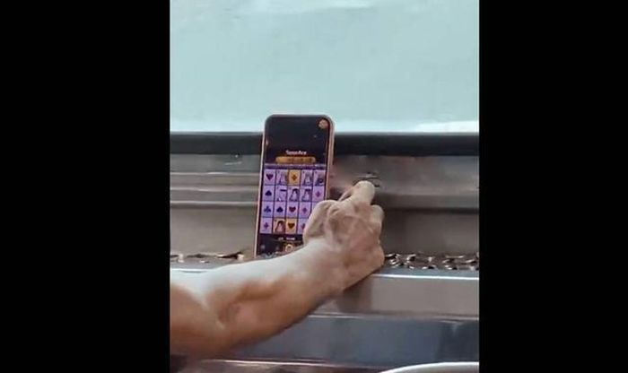 Tài xế bị ghi lại cảnh vừa lái xe vừa chơi game đánh bạc trực tuyến. Ảnh cắt từ clip/Newsflare