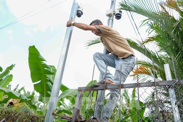 Anh Trần Quốc Khanh trèo qua hàng rào do hàng xóm dựng chắn lối vào nhà để đi làm. Ảnh: Thanh Liêm - TTXVN