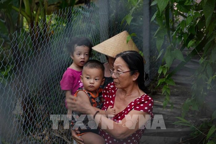 Bà Nguyễn Thị Nguyệt Minh cùng con dâu và hai cháu ngoại đứng bên trong hàng rào trò chuyện với phòng viên. Ảnh: Thanh Liêm - TTXVN