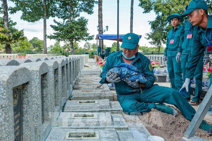 Các thành viên tổ lấy mẫu thực hiện công đoạn thu nhận mẫu hài cốt liệt sĩ tại Nghĩa trang Liệt sĩ Châu Thành. Ảnh: Minh Phú - TTXVN