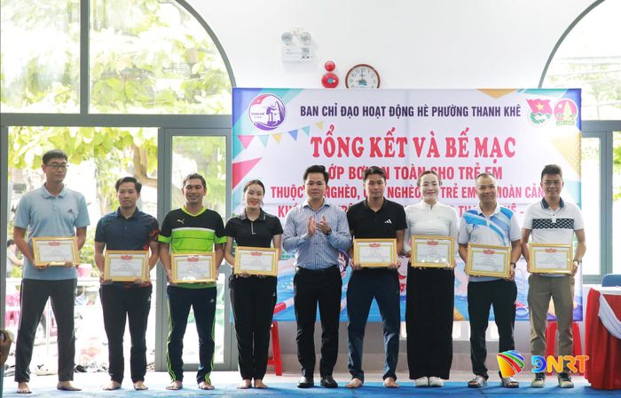 Đại diện lãnh đạo UBND phường Thanh Khê (giữa) trao giấy khen cho các giáo viên tham gia dạy bơi miễn phí cho học sinh nghèo. Ảnh: ĐẮC MẠNH