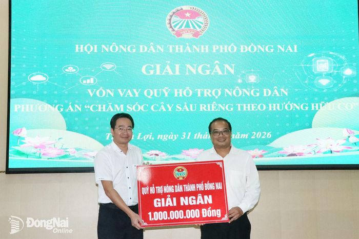 Phó Chủ tịch phụ trách Hội Nông dân thành phố Đồng Nai Nguyễn Văn Giang (trái) trao bảng tượng trưng giải ngân vốn vay cho Hội Nông dân xã Thuận Lợi. Ảnh: Quang Minh