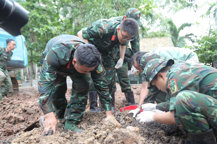 Bên cạnh những cán bộ dày dạn kinh nghiệm là hình ảnh những chiến sĩ trẻ tuổi đôi mươi miệt mài làm việc dưới nắng mưa. Họ cẩn trọng bóc từng nắm đất, nhẹ nhàng dùng bay nhỏ làm sạch từng lớp đất quanh những mảnh xương, chiếc cúc áo hay mẩu tăng võng đã nhuốm màu thời gian. Mỗi thao tác đều được thực hiện với sự tôn kính.