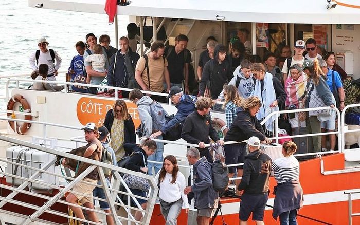Khách du lịch từ thành phố Lège-Cap-Ferret xuống thuyền ở xã Arcachon thuộc tỉnh Gironde, trong chiến dịch sơ tán toàn bộ bán đảo Cap-Ferret (điểm nghỉ dưỡng phổ biến của giới "nhà giàu" Bordeaux) ở phía Tây Nam nước Pháp ngày 24/7, khi cháy rừng lan rộng khắp khu vực. Ảnh: Romain Perrocheau/AFP