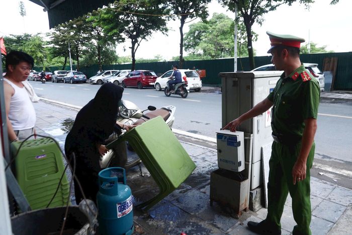 Tuyên truyền, yêu cầu các hộ kinh doanh tự giác tháo dỡ công trình, vật dụng lấn chiếm vỉa hè trên đường Hồng Đô. Ảnh: NT