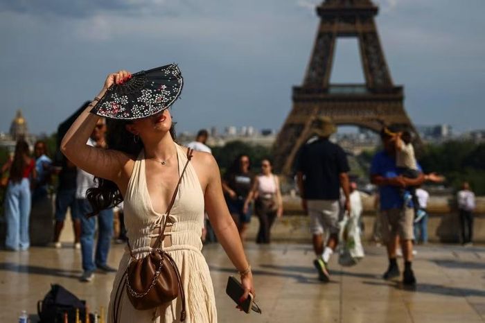  Một người phụ nữ đứng gần tháp Eiffel khi nhiệt độ lên cao ở Paris ngày 20/6. Ảnh: Reuters
