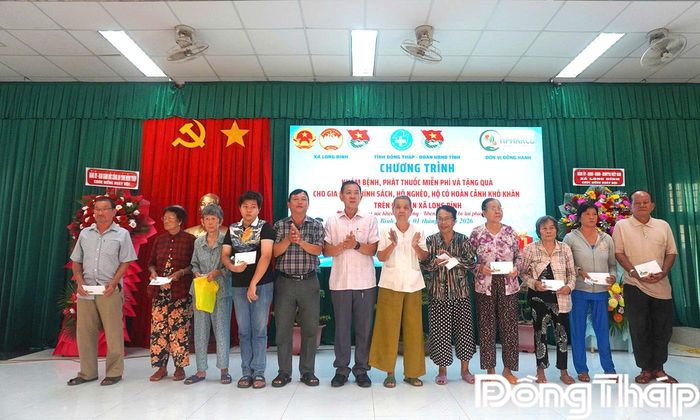 Đại tá Trần Văn Tròn cùng đồng chí Võ Ngọc Tân, Bí thư Đảng ủy, Chủ tịch HĐND xã, trao quà cho các hộ nghèo, hộ khó khăn, gia đình chính sách tại chương trình.