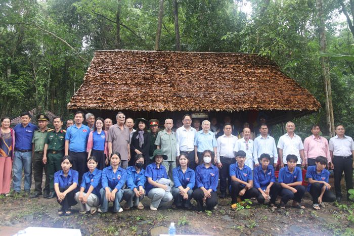 Đoàn khách tham quan mô hình nhà làm việc lợp bằng lá trung quân tại Khu căn cứ Sa Lôn