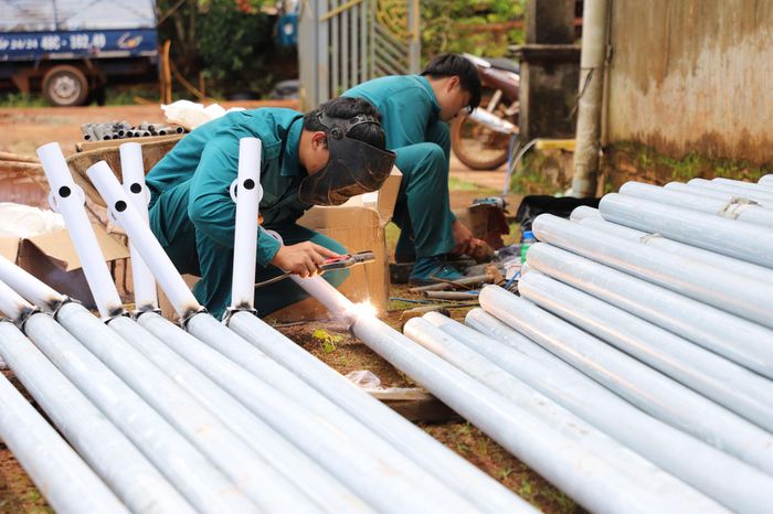 Lực lượng dân quân thường trực xã Quảng Trực hỗ trợ hoàn thiện các trụ đèn năng lượng