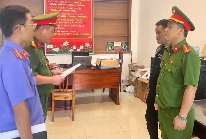 Cơ quan CSĐT Công an tỉnh Khánh Hòa tống đạt quyết định khởi tố bị can Nguyễn Quang Vinh (áo đen).