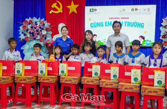 Chị Hà Ngọc Thảo, Bí thư Đoàn các Cơ quan Đảng tỉnh Cà Mau (bìa trái) và anh Lê Minh Hải, Phó Chủ tịch Thường trực Hội đồng Đội tỉnh Cà Mau (bìa phải) trao quà cho các em học sinh có hoàn cảnh khó khăn.