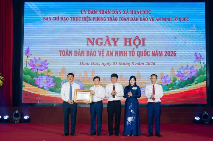 Ông Nguyễn Minh Long trao bằng khen của UBND thành phố Hà Nội cho Đảng bộ, chính quyền và nhân dân xã Hoài Đức do có thành tích trong phong trào toàn dân bảo vệ an ninh Tổ quốc. Ảnh: Hậu Lộc