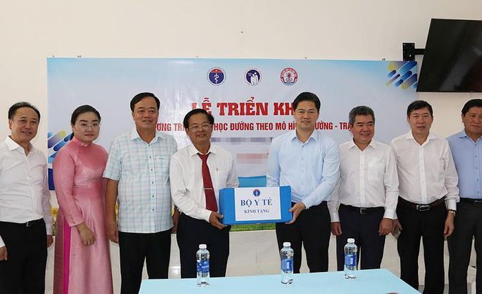 Thứ trưởng Thường trực Bộ Y tế tặng quà mừng mô hình Trường – Trạm chăm sóc răng miệng học sinh đi vào hoạt động. Ảnh: Ngân Phạm.