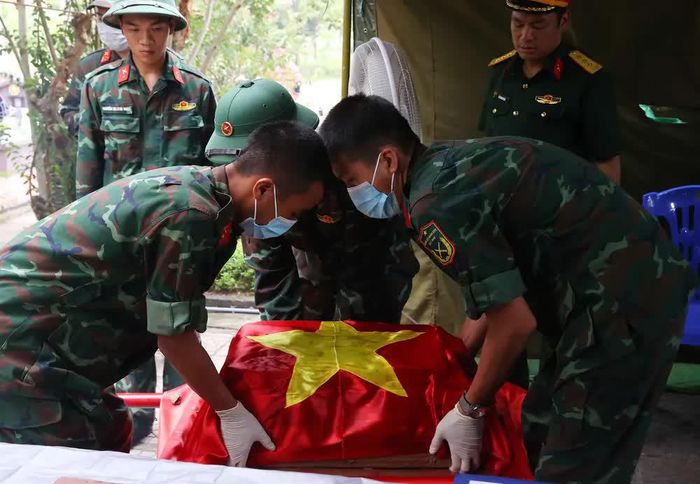 Thực hiện quy trình khai quật, đưa hài cốt liệt sĩ chưa xác định danh tính về khu vực lấy mẫu sinh phẩm tại Nghĩa trang liệt sĩ Nhổn (phường Tây Tựu). Ảnh: Văn Điệp – TTXVN