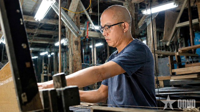 Nghệ nhân Lê Đăng Toản dệt lụa the bên khung dệt truyền thống tại xưởng của gia đình.