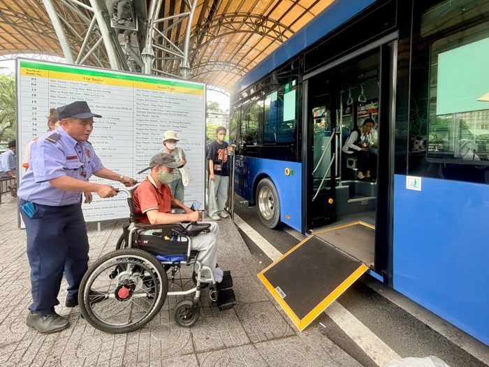 Nhân viên bến xe hỗ trợ hành khách sử dụng xe lăn lên xe buýt có sàn nâng tại Bến xe buýt Sài Gòn (Công viên 23 Tháng 9)