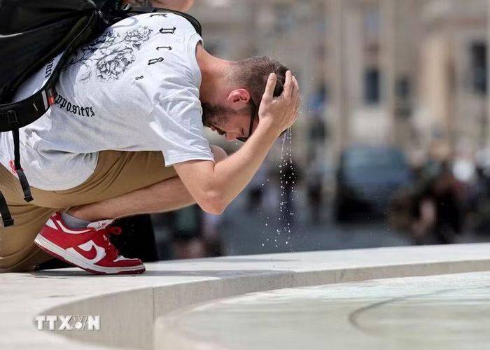 Một khách du lịch làm mát tại đài phun nước ở Rome, Italy. (Ảnh: THX/TTXVN phát)