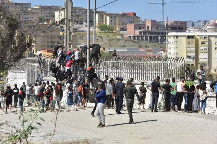 Người di cư trèo qua hàng rào biên giới để vào vùng lãnh thổ Ceuta của Tây Ban Nha từ thành phố Fnideq, Maroc. (Ảnh: THX/TTXVN phát)