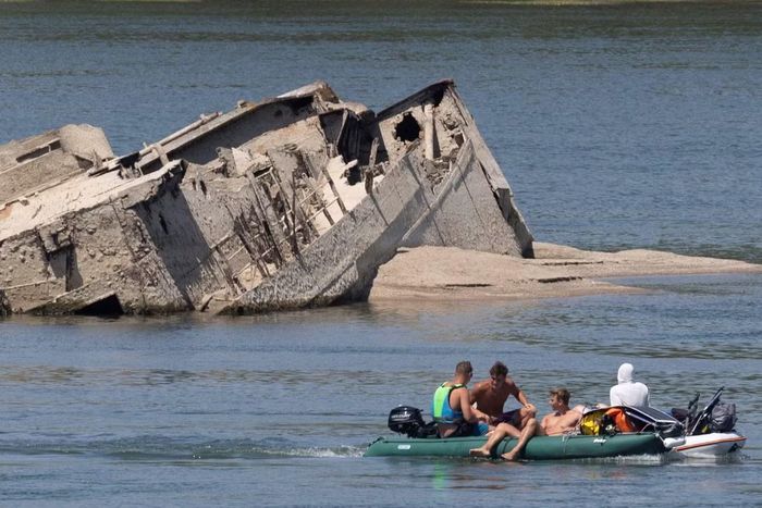 Người dân bơi trên sông quan sát xác chiến hạm. Ảnh: Reuters.