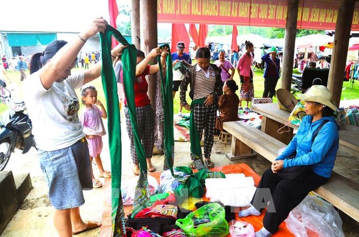 Người dân và du khách lựa chọn, thử những bộ trang phục truyền thống của đồng bào dân tộc thiểu số tại chợ phiên vùng cao, góp phần gìn giữ và quảng bá nét đẹp văn hóa bản địa. Ảnh: Xuân Tiến - TTXVN