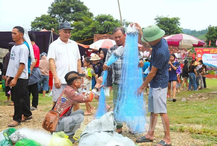 Nhiều đàn ông đang lựa chọn kỹ độ mảnh của sợi đan, kích thước mắt lưới trên từng tấm lưới để mua về phục vụ công việc đánh bắt cá trên sông, suối. Ảnh: Xuân Tiến - TTXVN