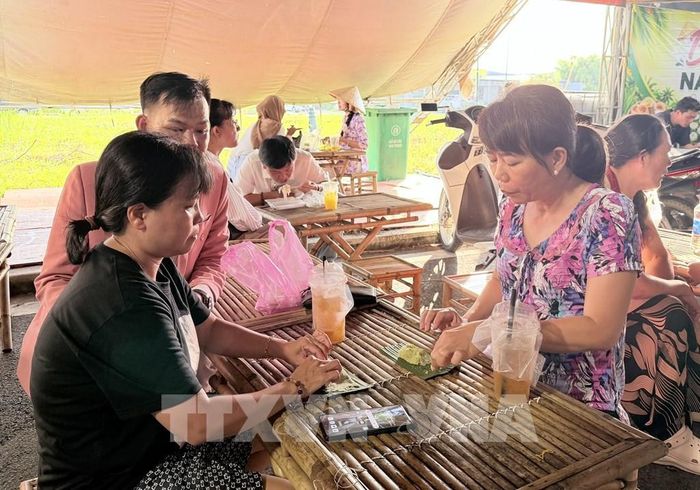 Du khách thích thú thưởng thức bánh rây món bánh truyền thống của đồng bào Khmer An Giang. Ảnh: Thanh Sang- TTXVN