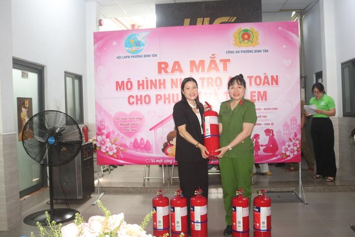Trung tá Ngô Thùy Dương, Phó trưởng Công an phường Bình Tân, trao bình chữa cháy cho đại diện khu nhà trọ.