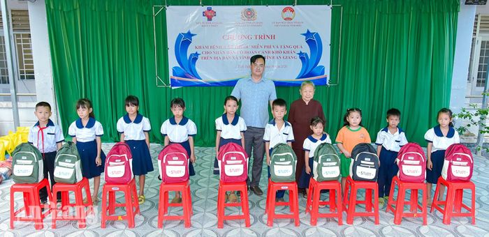 Chủ tịch Ủy ban MTTQ Việt Nam xã Vĩnh Điều Nguyễn Văn Dức cùng nhà tài trợ trao cặp cho học sinh.