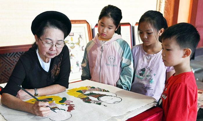 Nghệ nhân Ưu tú Nguyễn Thị Oanh hướng dẫn thiếu nhi cách làm tranh.