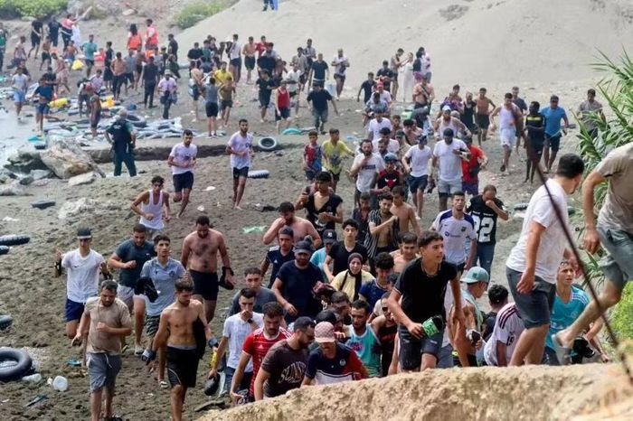 Hàng trăm người di cư di chuyển hỗn loạn trên bãi biển ở Ceuta hôm 31/7 sau khi bơi qua từ Morocco. Ảnh: DPA