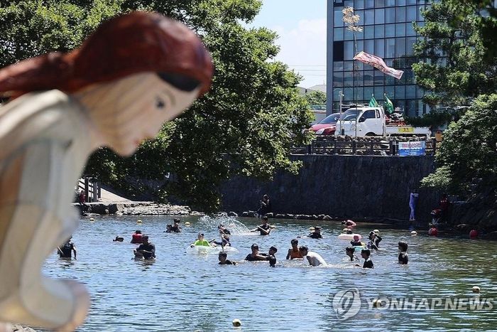 Người dân và du khách giải nhiệt tại khu vực suối Woldaecheon, phường Oedo, thành phố Jeju, Hàn Quốc. Ảnh: Yonhap.