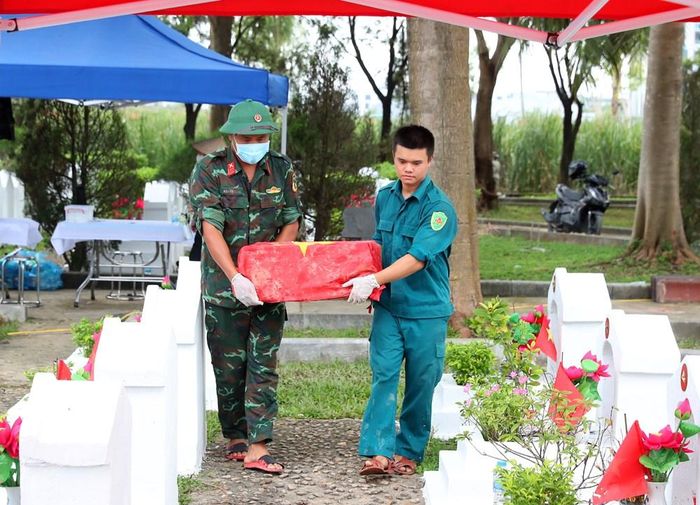 Các lực lượng đưa hài cốt liệt sĩ trở lại phần mộ sau khi hoàn tất quy trình lấy mẫu