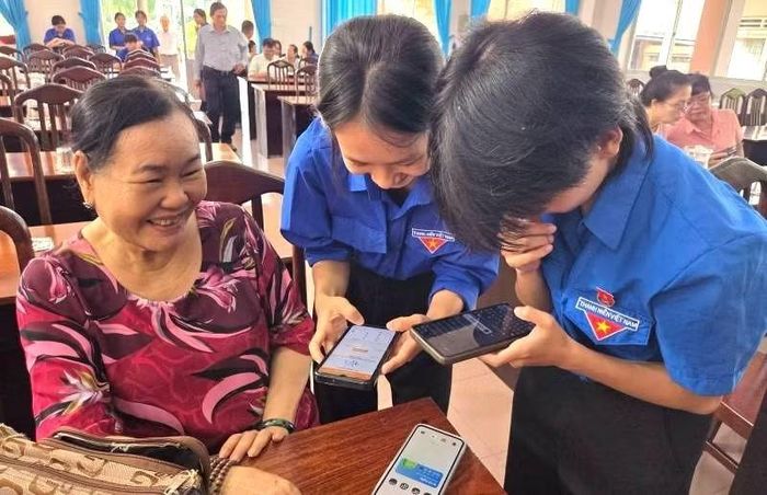 Lực lượng Đoàn Thanh niên phường Long An hướng dẫn người cao tuổi cài đặt phần mềm ứng dụng không tiền mặt và sổ tay đảng viên.