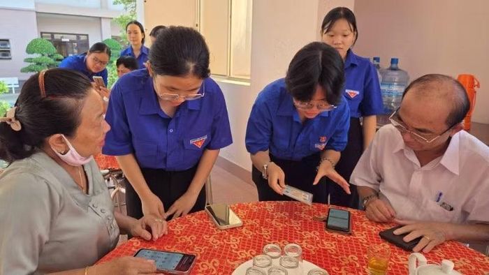 Lực lượng Đoàn Thanh niên phường Long An hướng dẫn người cao tuổi cài đặt phần mềm ứng dụng không tiền mặt và sổ tay đảng viên.