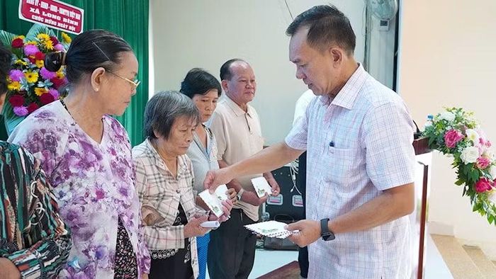 Đại tá Trần Văn Tròn, Phó Giám đốc Công an tỉnh Đồng Tháp cùng Ban tổ chức trao quà tặng các gia đình chính sách, hộ nghèo, hộ có hoàn cảnh khó khăn trên địa bàn xã Long Bình.