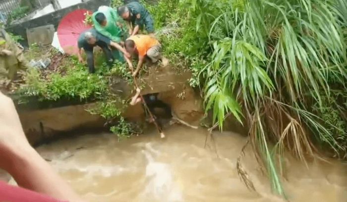 Người dân đang cứu hộ một thiếu niên gặp nạn do nước lũ cuốn.