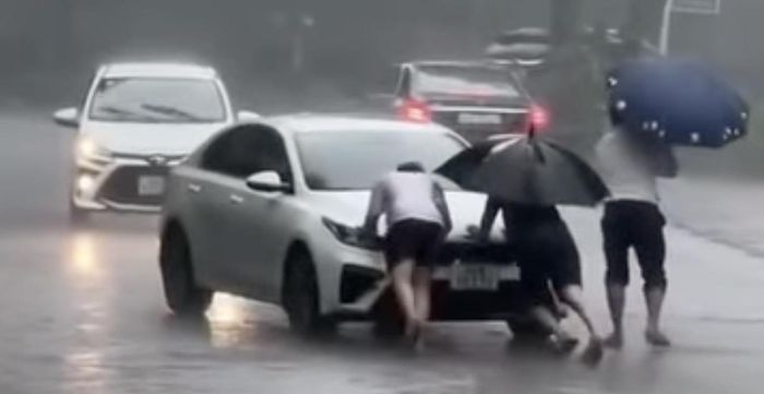 Một ô tô không thể di chuyển qua khu vực ngập sâu được người dân giúp đỡ thoát hiểm. Ảnh: Cắt từ Clip