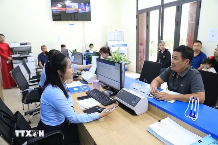 Cán bộ Điểm hỗ trợ dịch vụ công số Thư Lâm hướng dẫn người dân hoàn thiện hồ sơ, thủ tục hành chính. (Ảnh: Trung Nguyên/TTXVN)