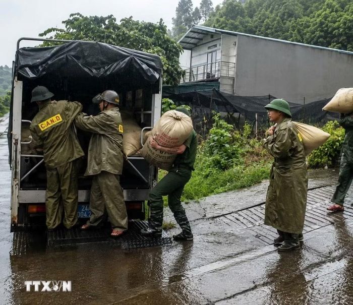 Lực lượng Công an lào Cai hỗ trợ người dân di chuyển tài sản ra khỏi khu vực có nguy cơ sạt lở. (Ảnh: TTXVN phát)