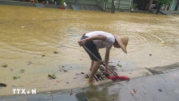 Người dân tổ 4 Duyên Hải, phường Lào Cai khơi thông cống rãnh thoát nước ngập úng. (Ảnh: Hương Thu/TTXVN)
