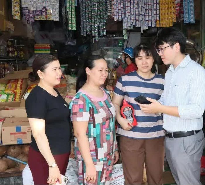 Tiểu thương chợ Đồng Xoài được hướng dẫn cài đặt phần mềm. Ảnh: Quang Minh.