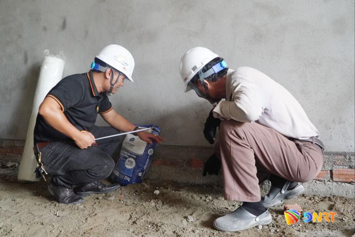 Ông Trần Vương Khiết (bên trái) hướng dẫn cho kỹ thuật viên cách phòng ngừa thấm nứt chân tường trong xây dựng dân dụng. Ảnh: PHAN VINH