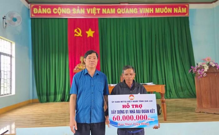 Đồng chí Trần Minh Sơn trao kinh phí hỗ trợ xây dựng nhà "Đại đoàn kết" cho gia đình chính sách làng Nang Long - O Sơr. Ảnh: Bá Bính