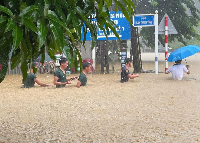 Lực lượng bộ đội, công an hỗ trợ người dân di chuyển đến nơi an toàn và khắc phục hậu quả sau mưa lũ. (Ảnh: Đình Văn)