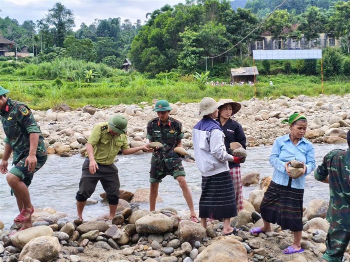 Những hòn đá được cán bộ, chiến sĩ và người dân chuyền tay nhau để gia cố hệ thống rọ thép. Ảnh: Thúy Hằng