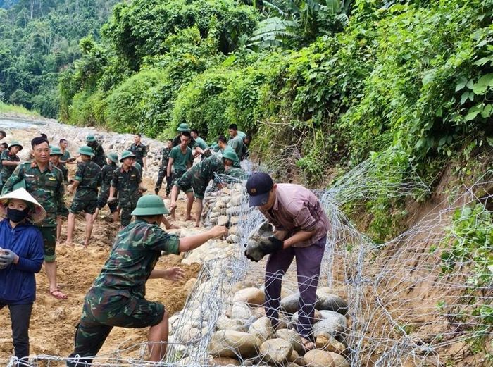 Những hòn đá được cán bộ, chiến sĩ và người dân chuyền tay nhau để gia cố hệ thống rọ thép. Ảnh: Thúy Hằng