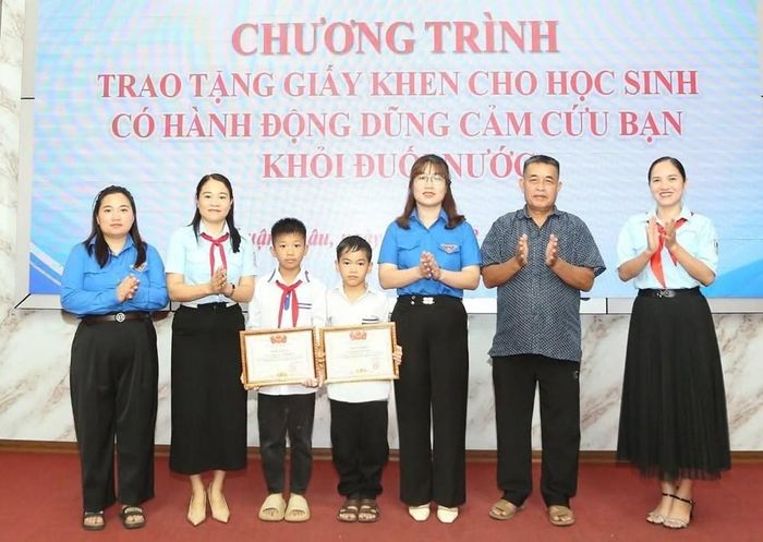 Đại diện Đoàn xã Thuận Châu chuyển trao Giấy khen của Hội đồng Đội tỉnh Sơn La cho 2 em Tòng Văn Khắc Huy và Lường Hải Nam