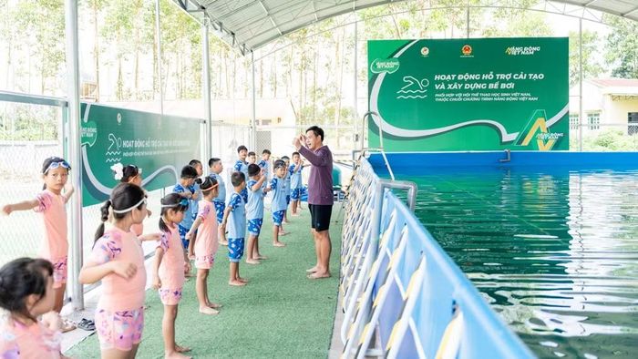Thầy giáo hướng dẫn các bạn học sinh khởi động trước khi xuống bể.